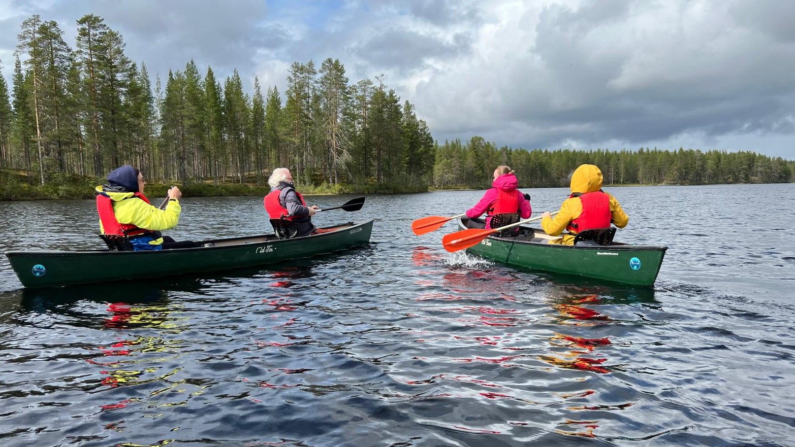 kaksi kanoottia, joissa molemmissa 2 henkilöä. Ranta on suhteellisen lähellä.
