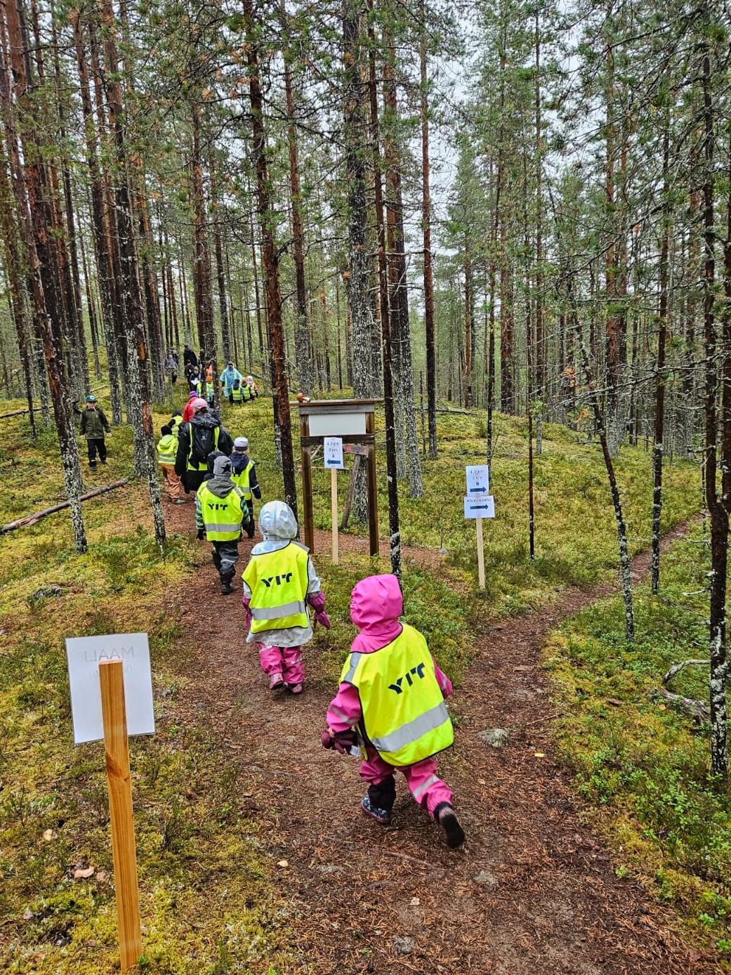 Pieniä lapsia huomioliiveissä metsäpolulla.