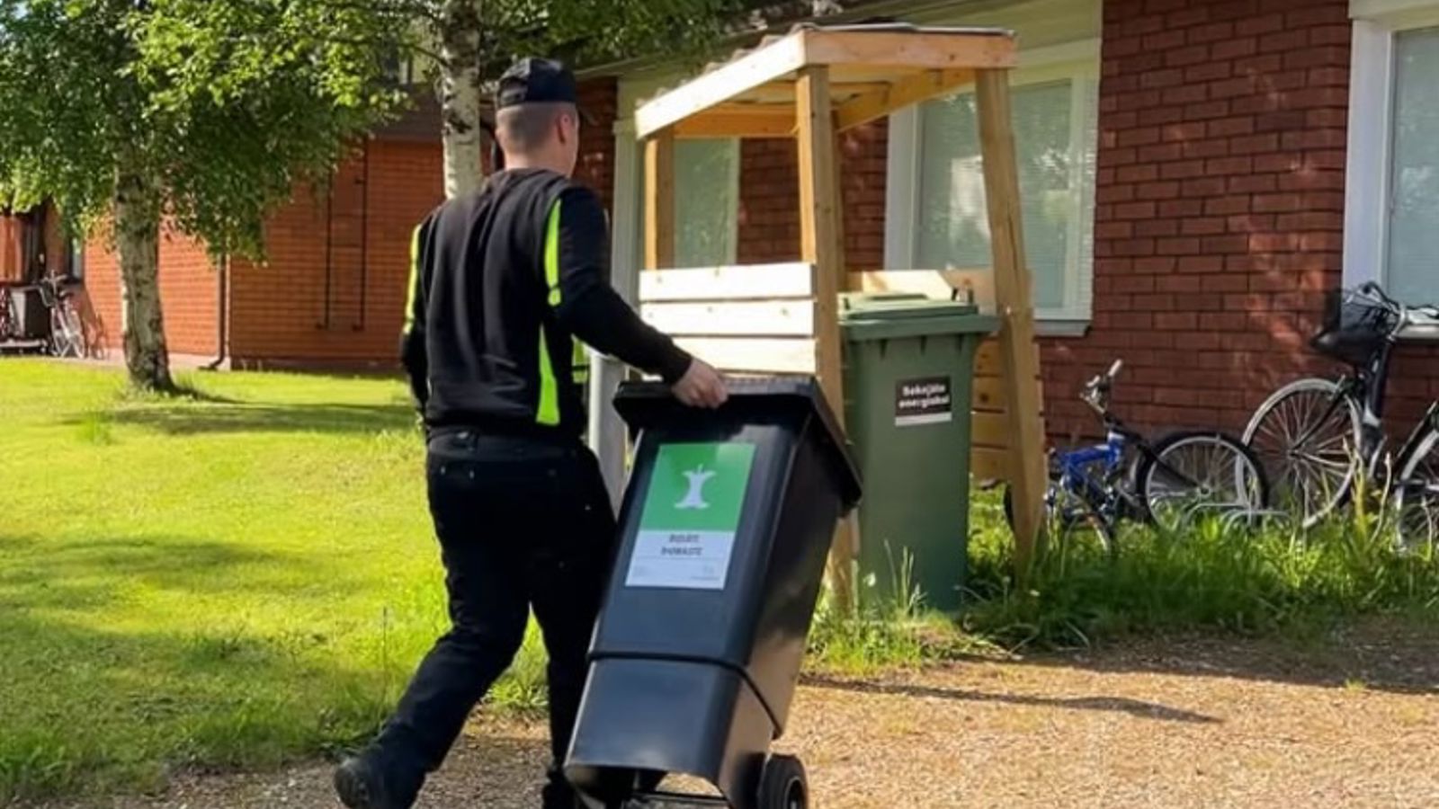 Kesällä otettu kuva henkilöstä, joka kuljettaa biojäteastiaa.